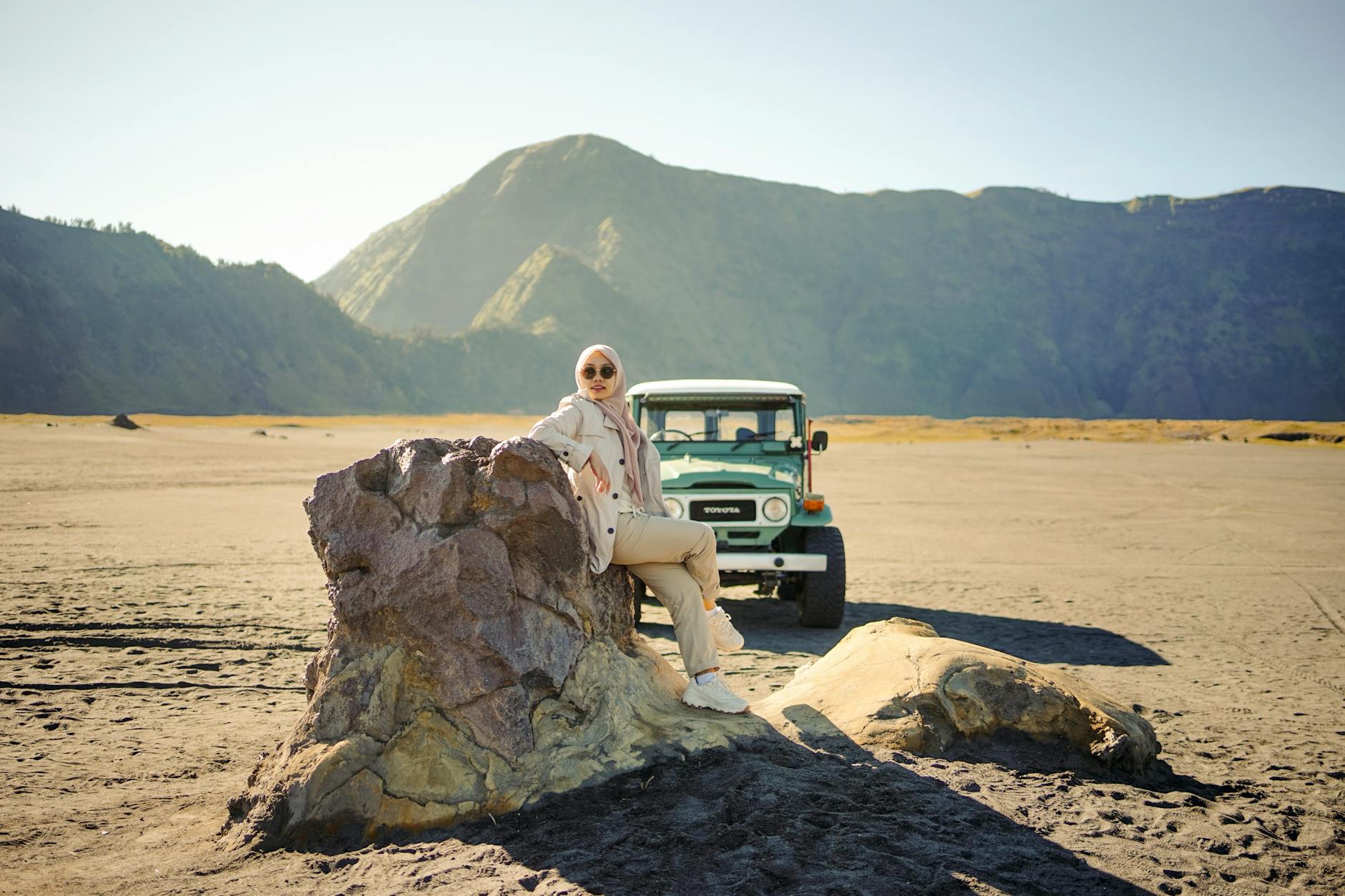 Kobieta w hidżabie obok terenowego auta na tle wulkanu Bromo