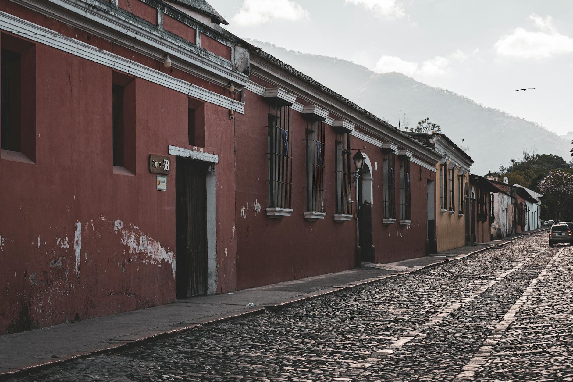 Kolorowa kolonialna uliczka Antigua Guatemala z brukiem i górami w tle