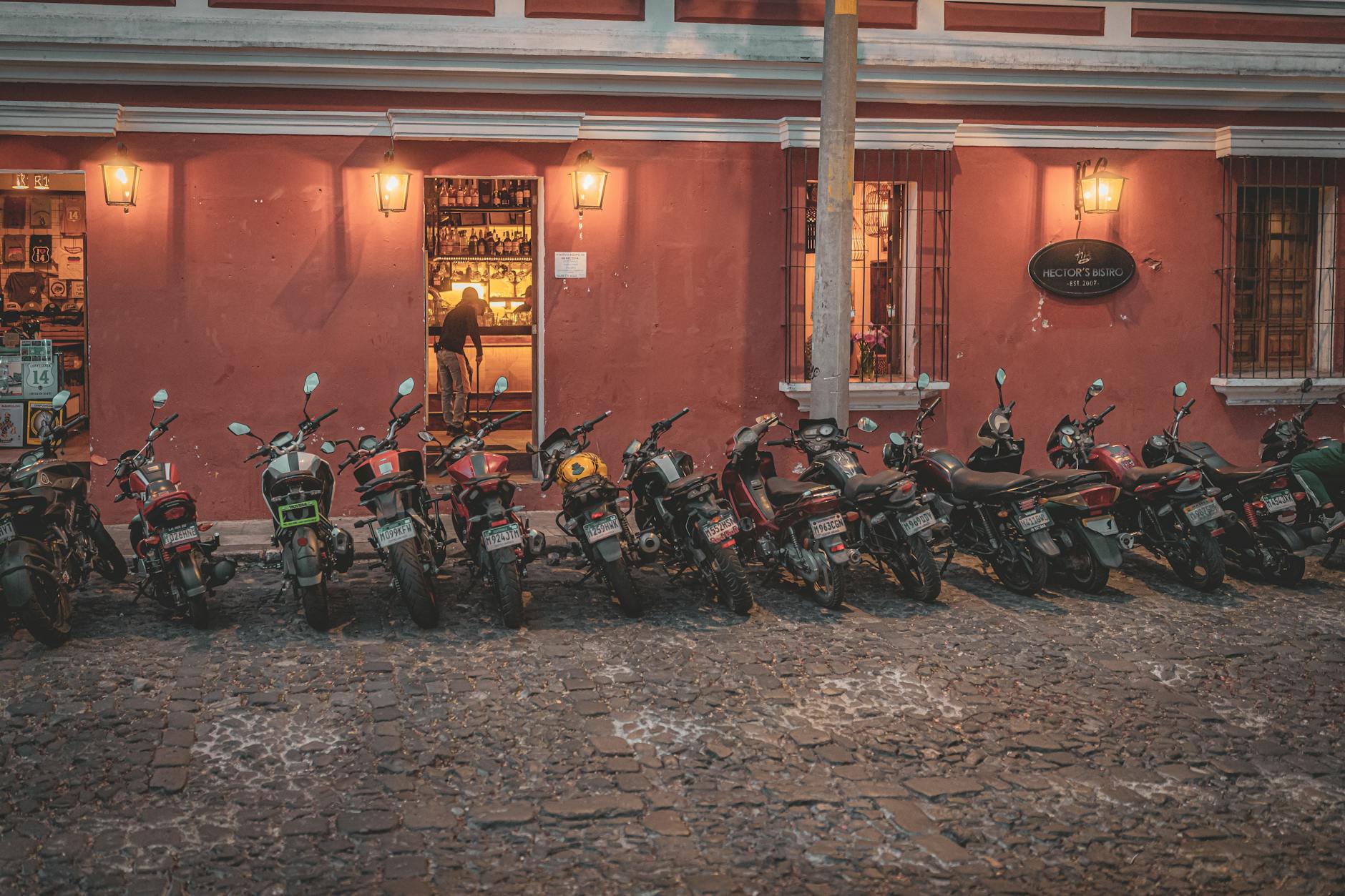 Motocykle zaparkowane przed barem przy brukowanej ulicy w Antigua Guatemala