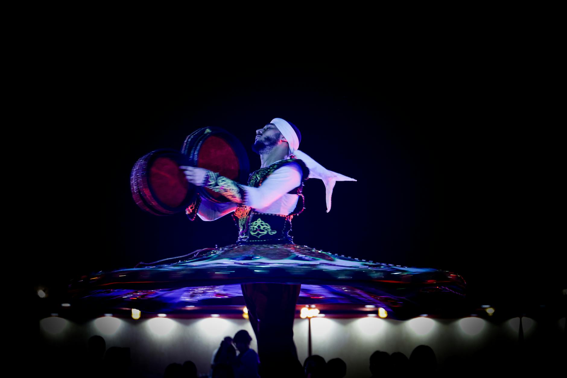 Wirujący derwisz w kolorowym stroju podczas nocnego sufickiego występu