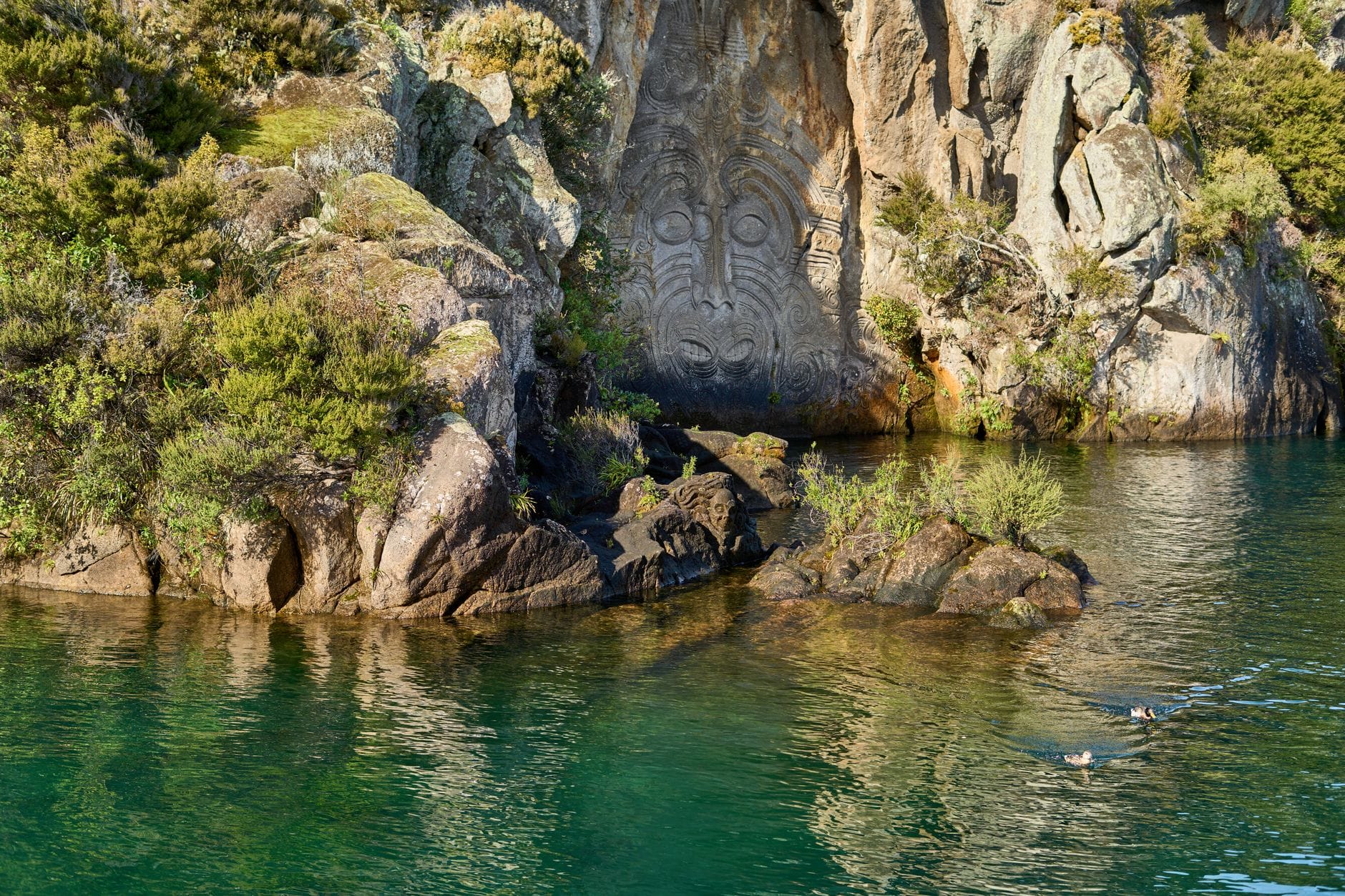 Maoryskie rzeźby skalne w Mine Bay nad jeziorem Taupō otoczone zielenią