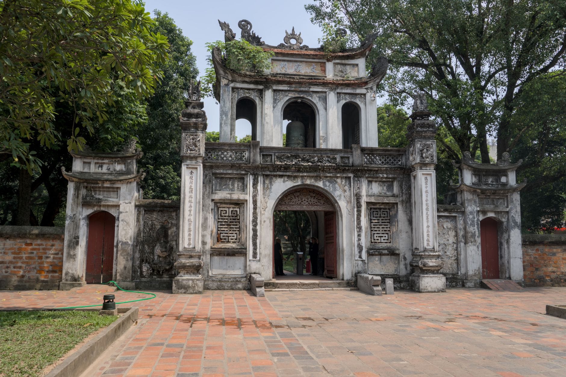 Zabytkowa brama świątyni w Hanoi otoczona bujną zielenią