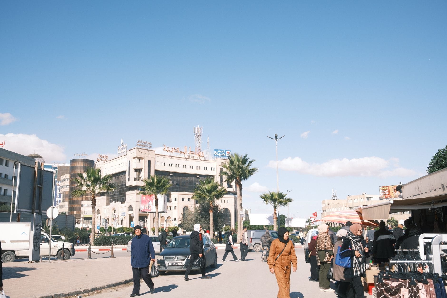 Targowisko uliczne w Sfax z mieszkańcami, straganami i samochodami
