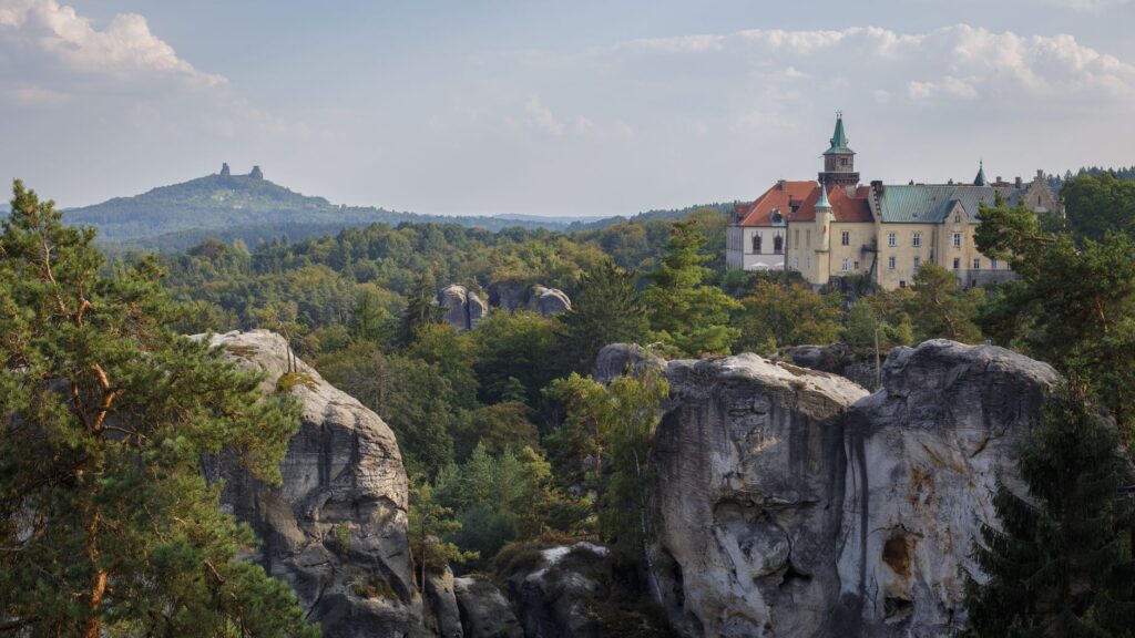 Zamek Hrubá Skála wśród skalnych formacji i zieleni